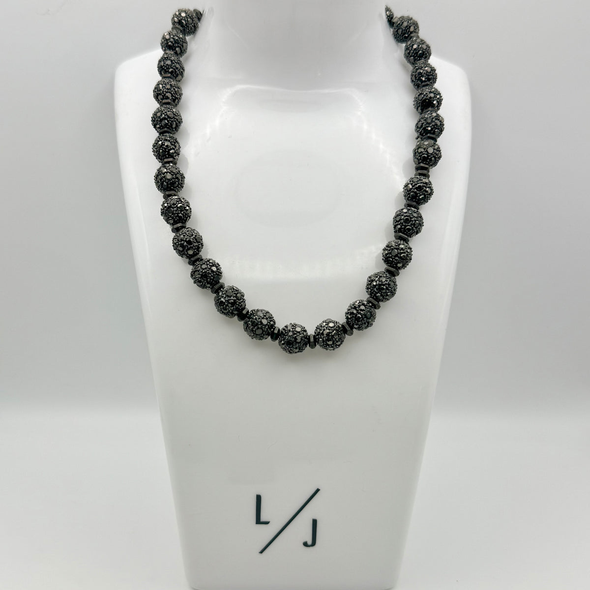 Black beaded necklace on a white mannequin bust with 'LJ' logo.
