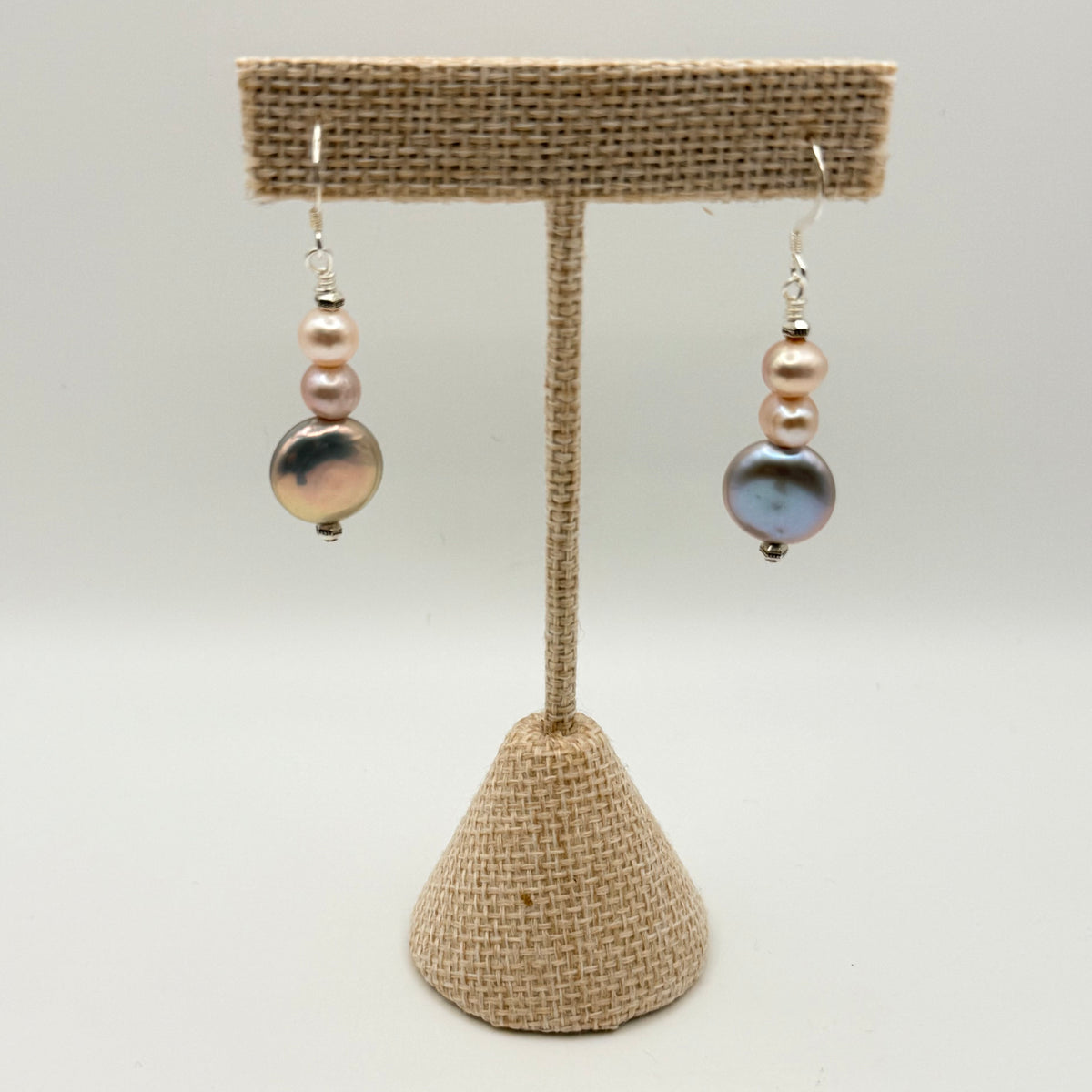 Pair of earrings on a burlap stand against a white background