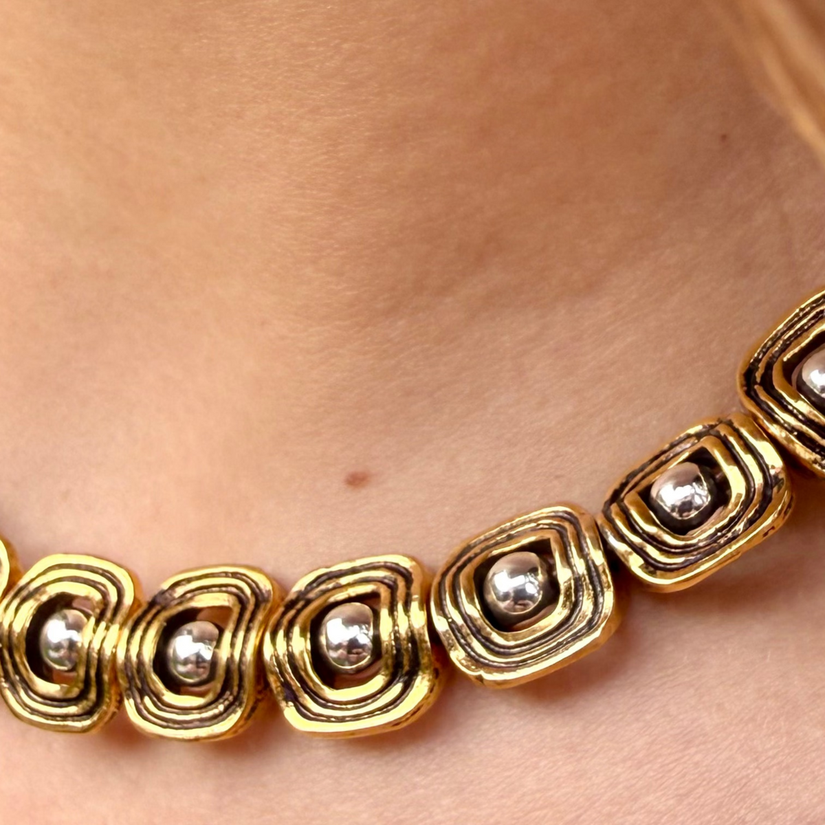 Gold necklace with circular design on a person's neck