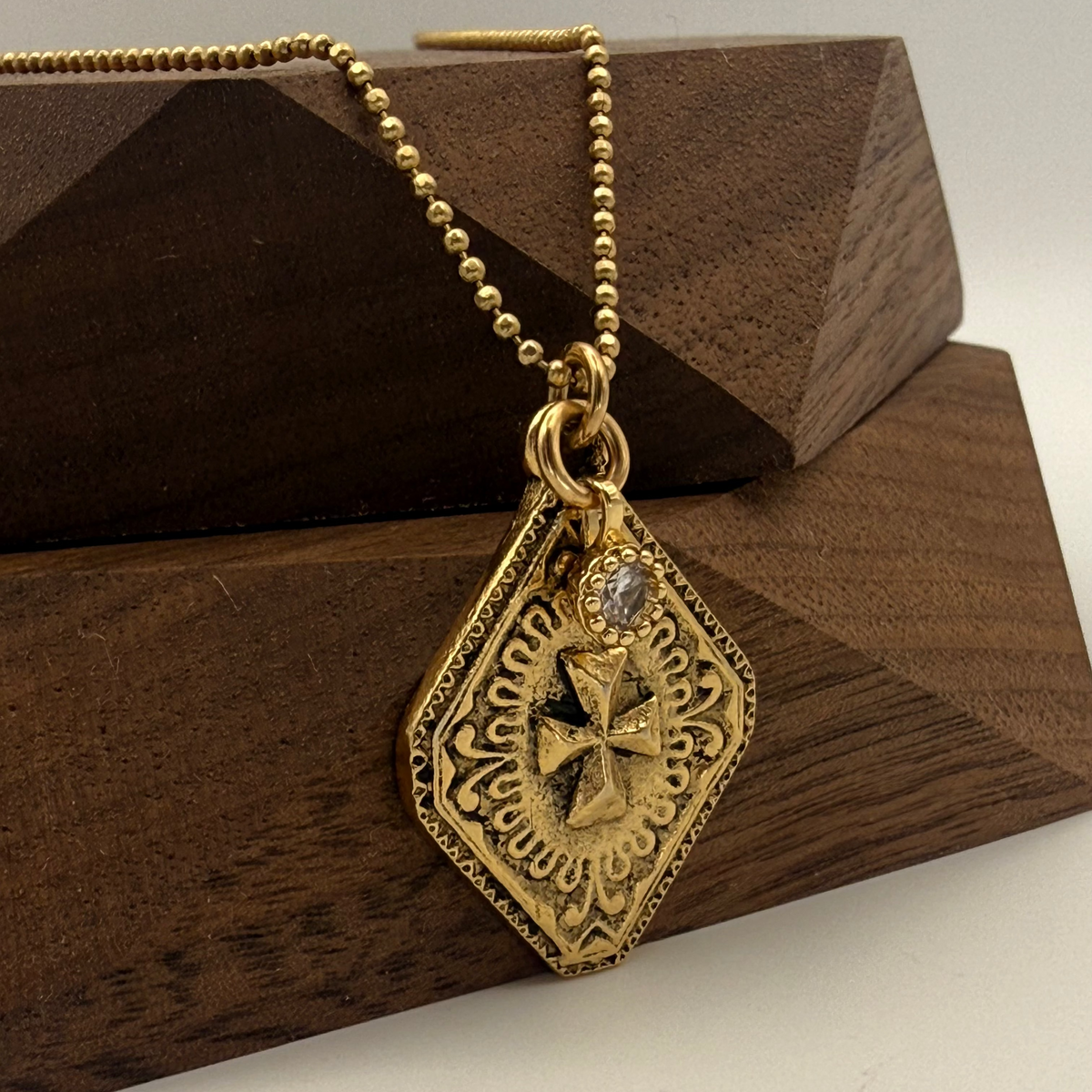 Gold necklace with a decorative pendant on a wooden stand