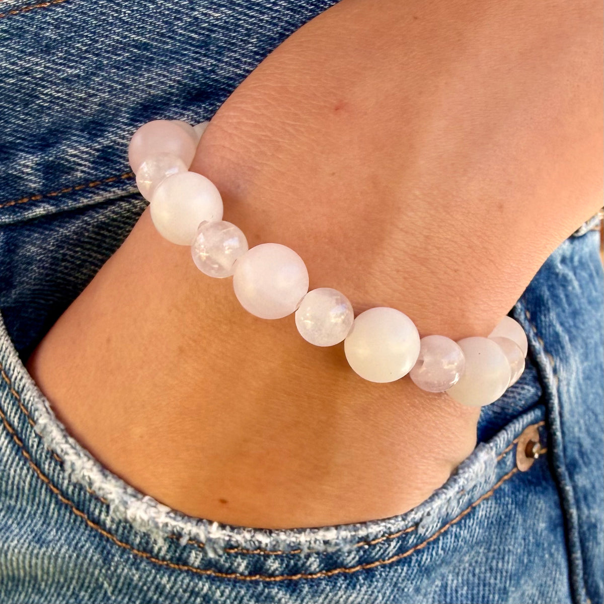 Close up of the Amelie Rose Quartz Bracelet featuring alternating larger matte and smaller polished pale pink rose quartz beads on a woman's wrist.