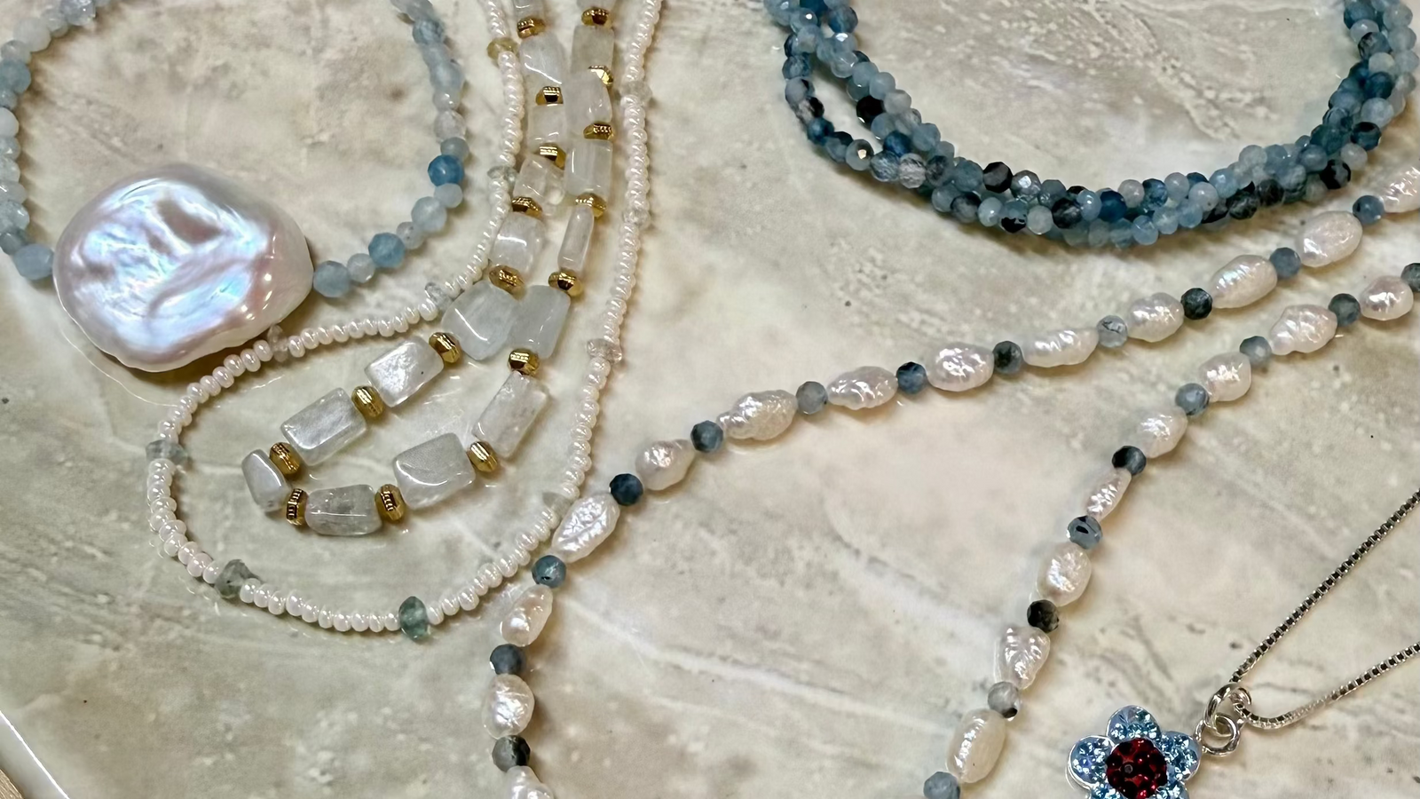 Collection of pearl and gemstone jewelry on a textured surface