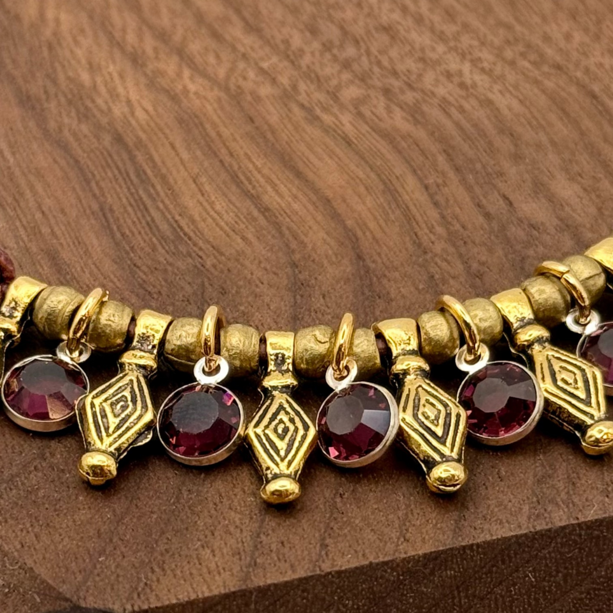 Bracelet with gold and red beads on a wooden stand