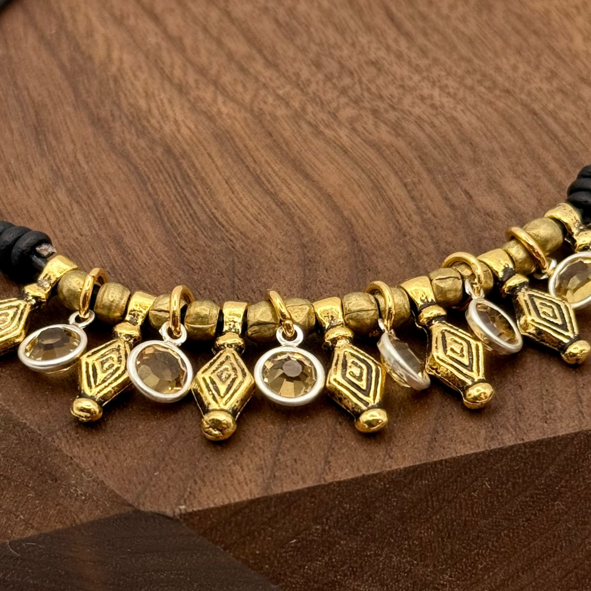 Gold and black beaded bracelet on a wooden stand