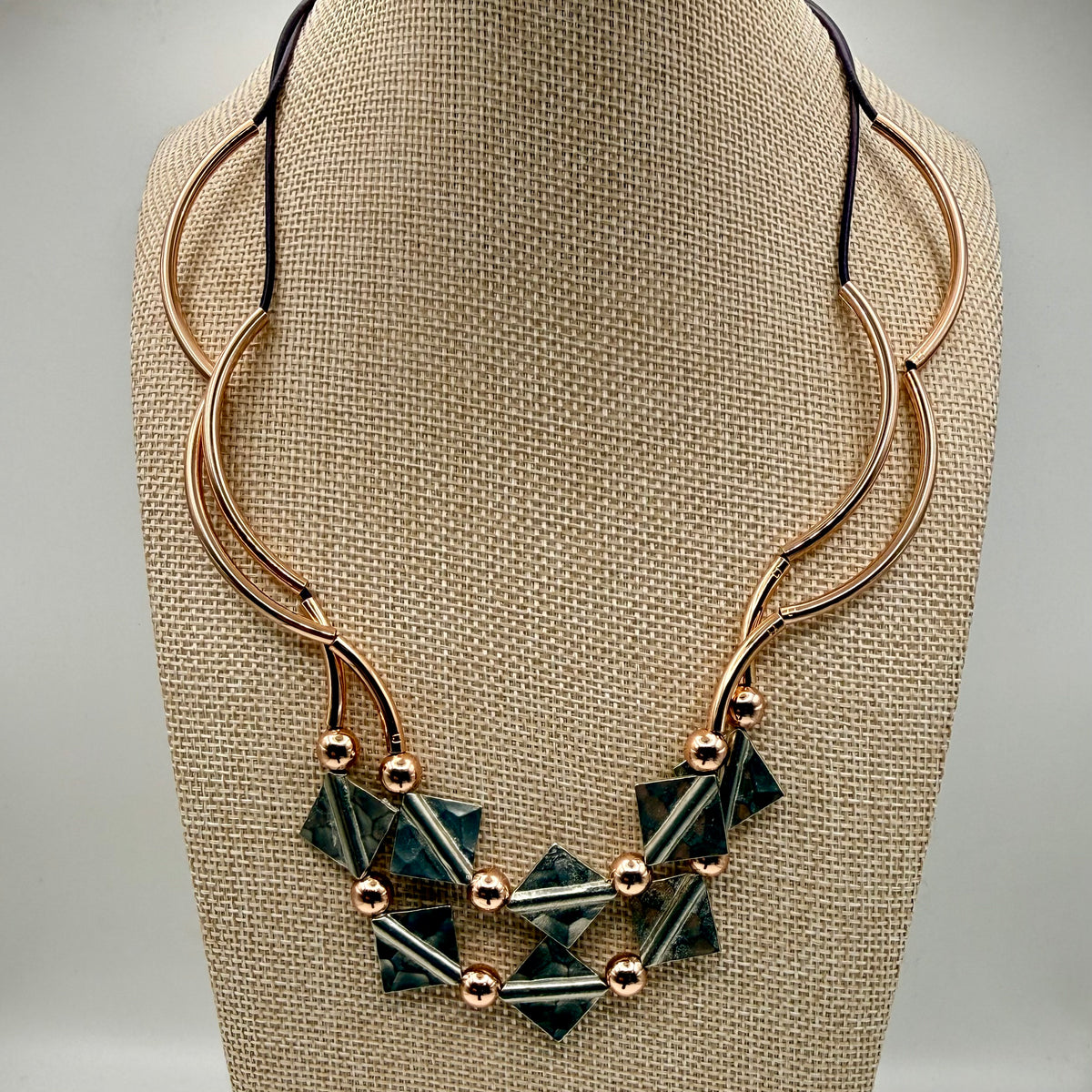 Necklace with geometric pendant on a beige fabric stand
