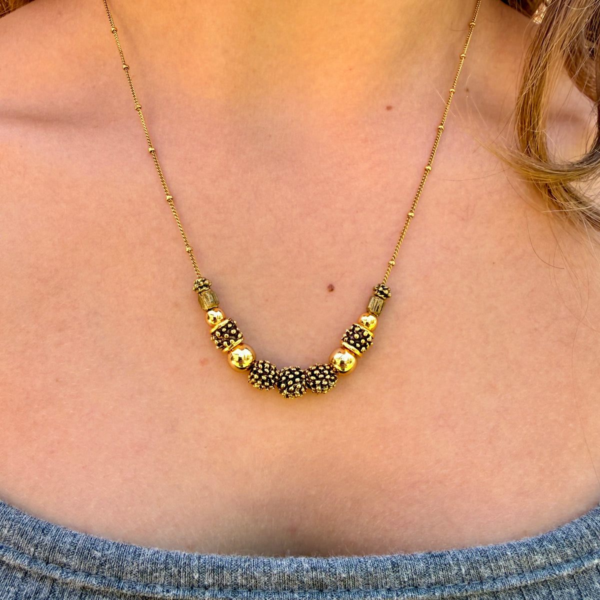 Necklace with gold and black beads worn by a person