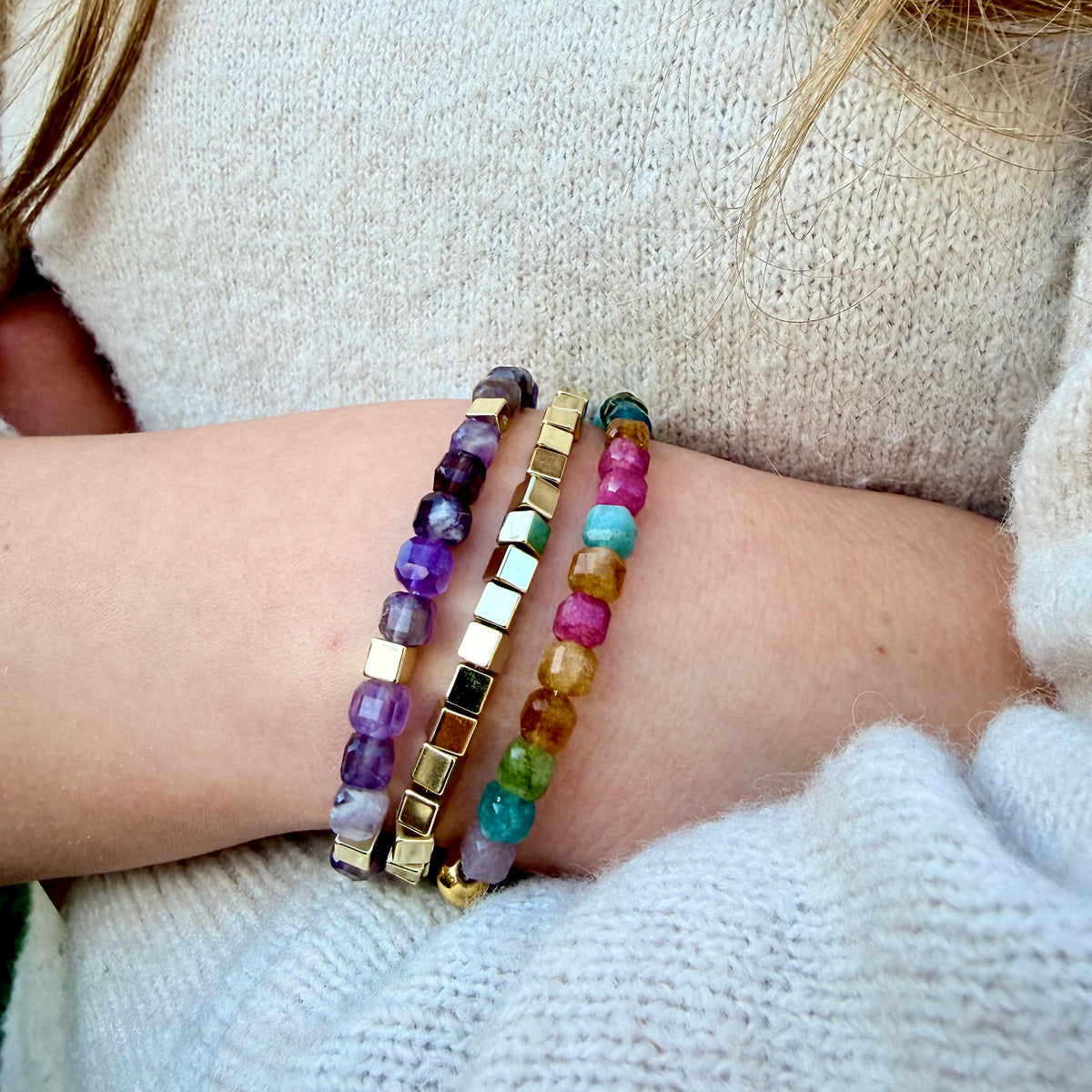 Close-up of a wrist wearing colorful beaded bracelets on a neutral background
