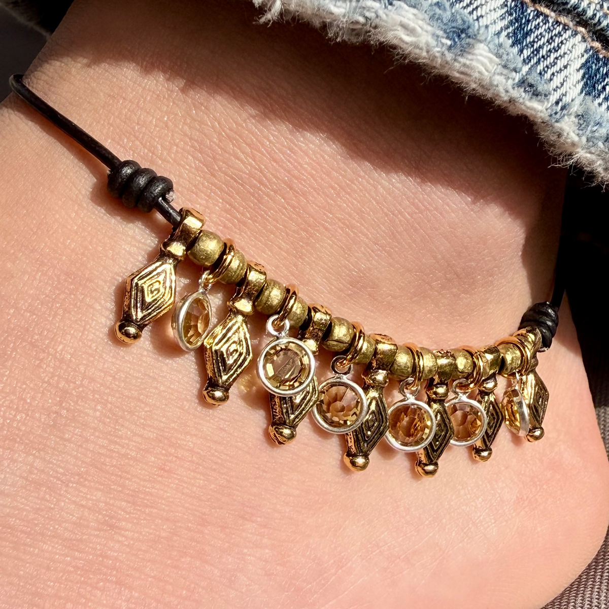 Khaleesi citrine crystal anklet with black leather, gold charms, and yellow crystal dangles