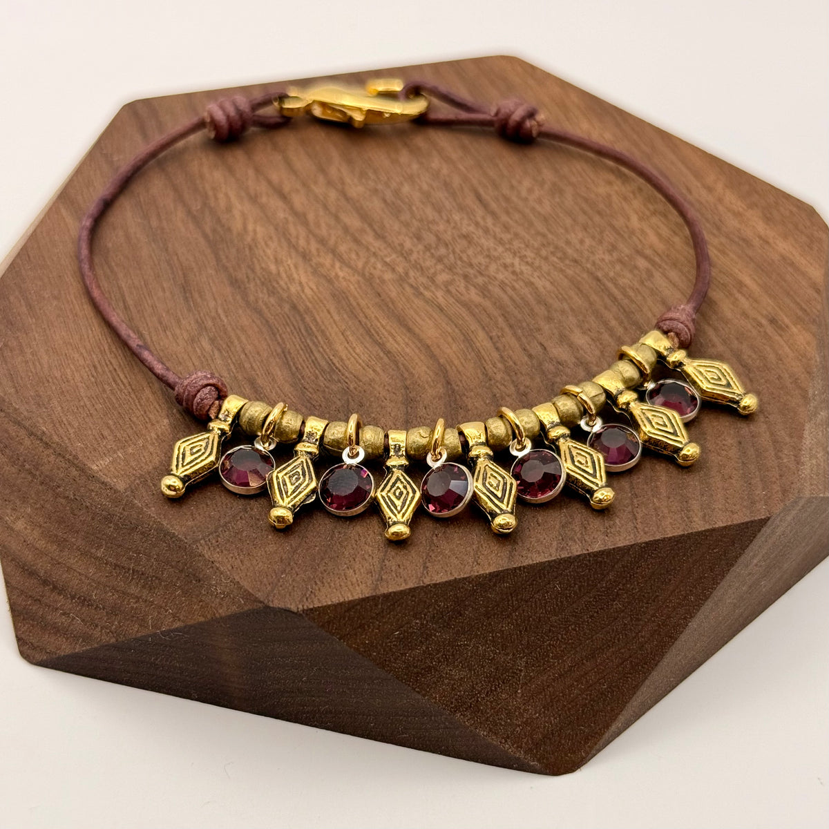 Bracelet with gold and red beads on a wooden stand
