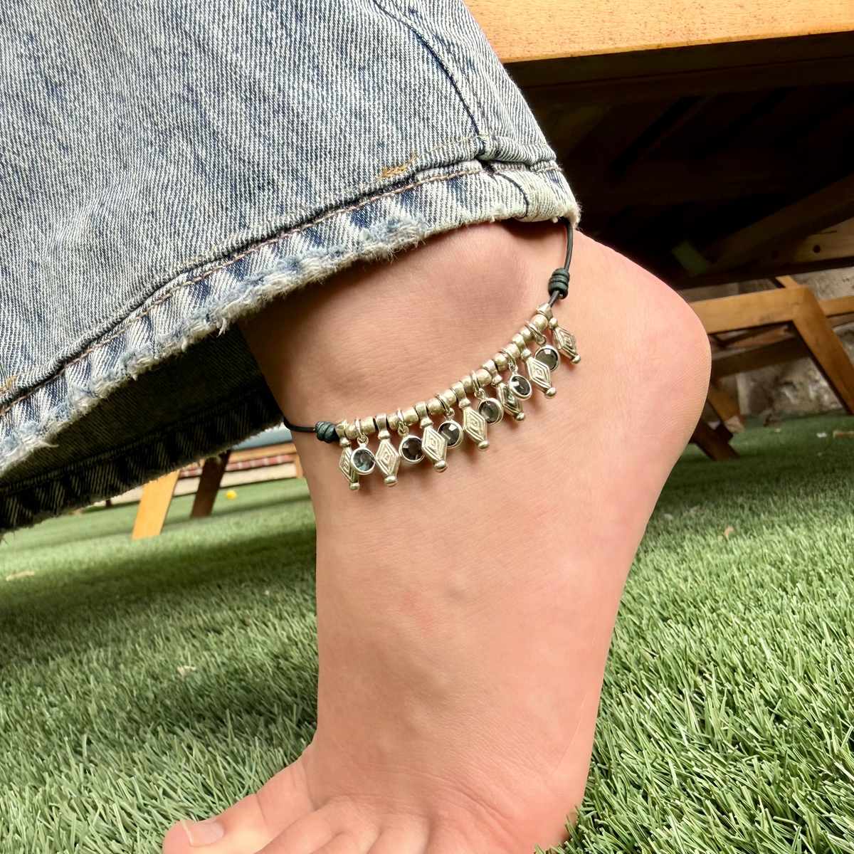 Person wearing a beaded anklet on a grassy surface