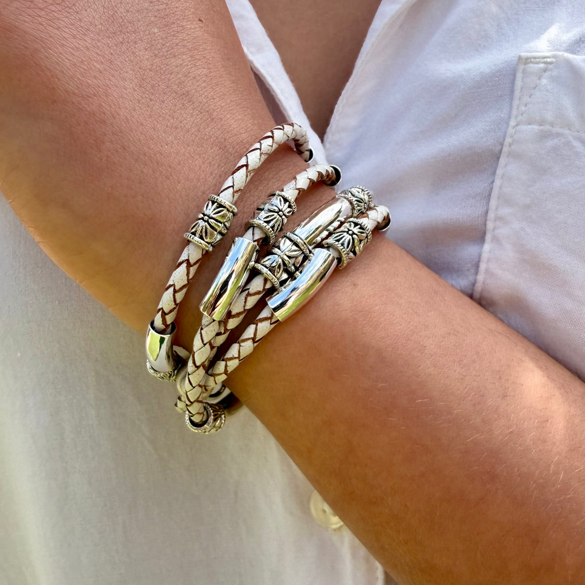 Close-up of a wrist wearing multiple bracelets on a neutral background