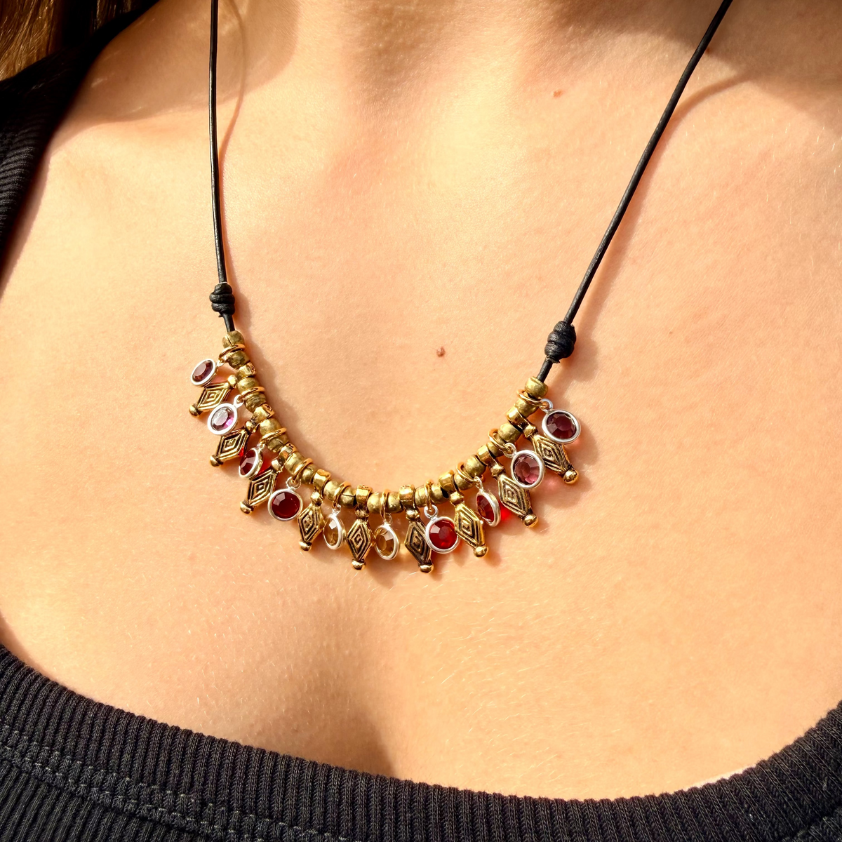Naya Warm Crystal Necklace with garnet, ruby, and citrine crystals on black leather with antique gold charms