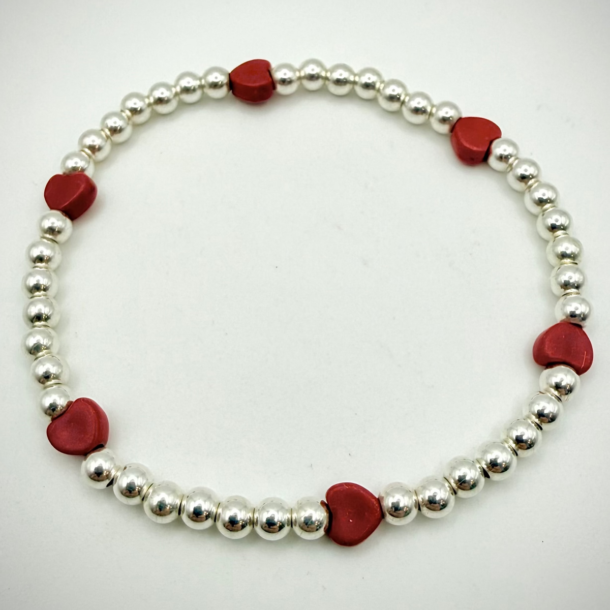 Bracelet with alternating red heart-shaped beads and silver beads on a white background