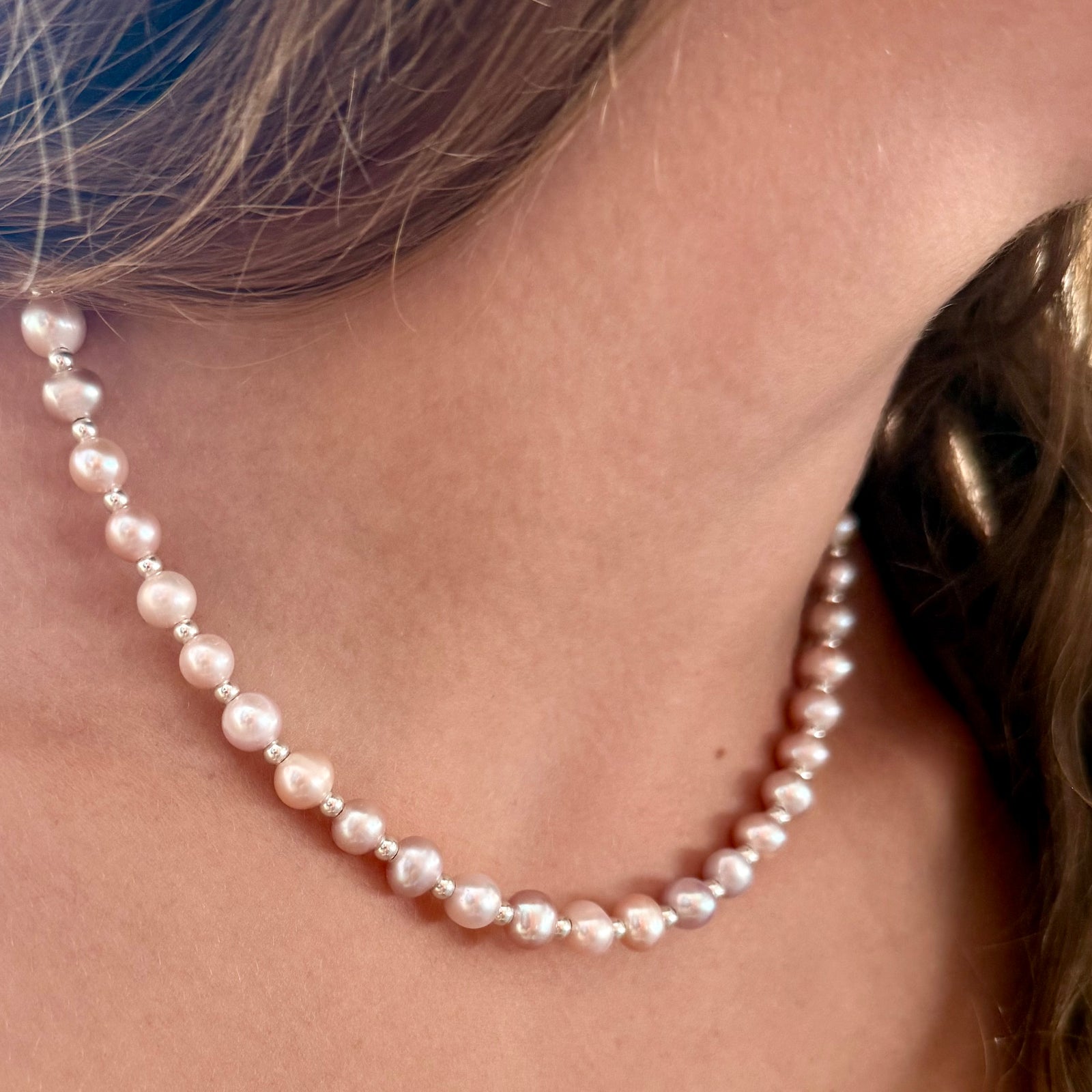 Woman wearing the Roselle pink freshwater pearl necklace with silver-plated accents