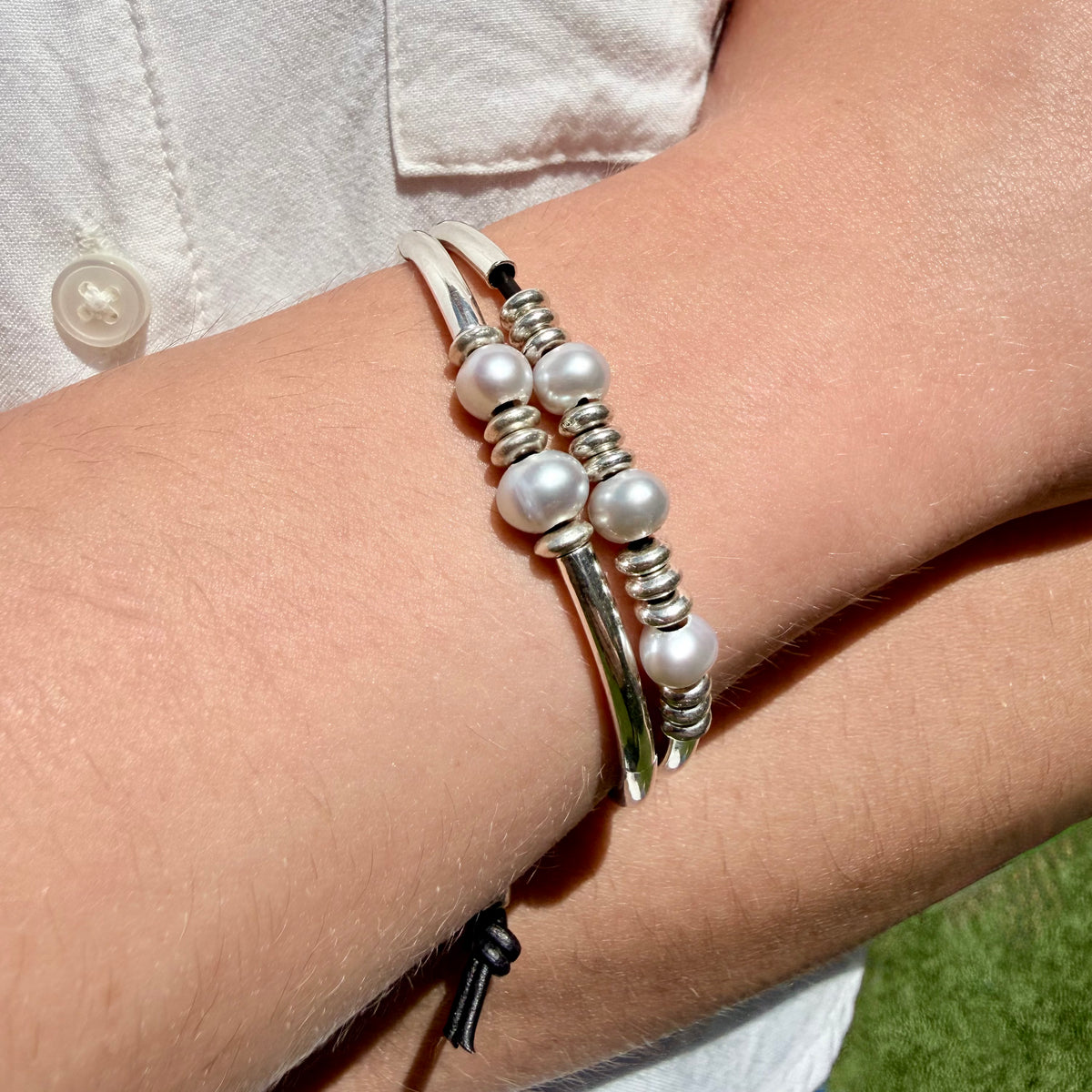 Silver and pearl bracelet on a wrist with a blurred background