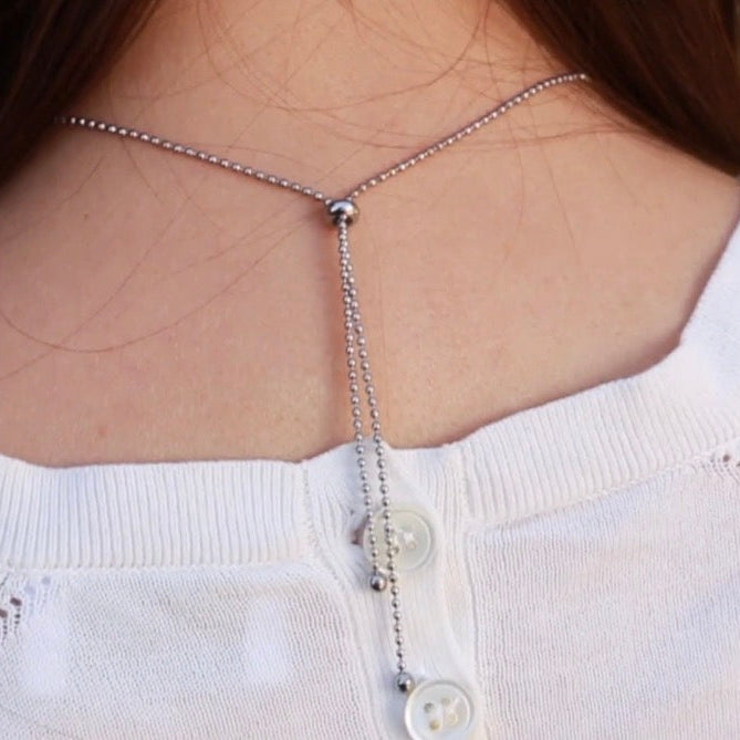 Necklace with a pendant on a person wearing a white sweater.