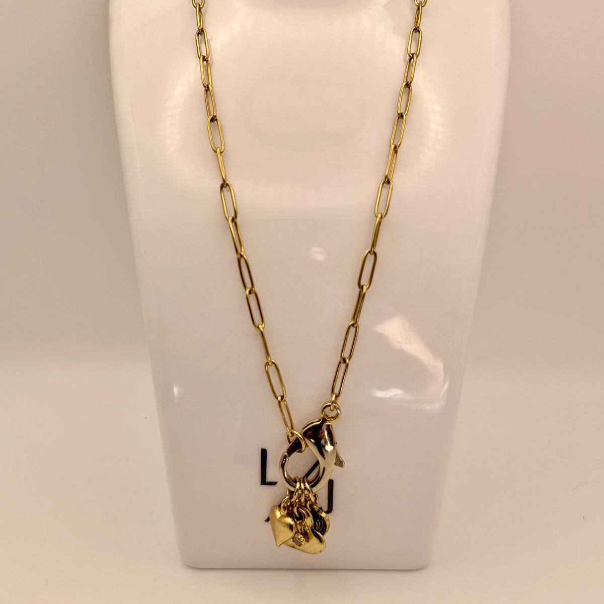 Gold necklace with heart charm on a white mannequin bust