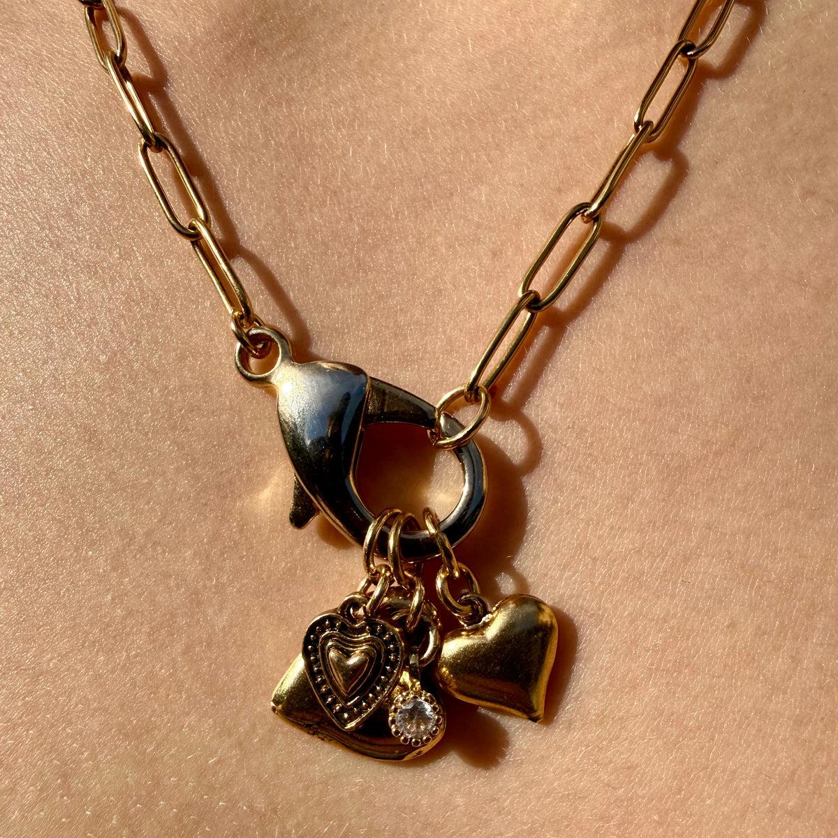 Gold necklace with heart-shaped pendants on a beige background