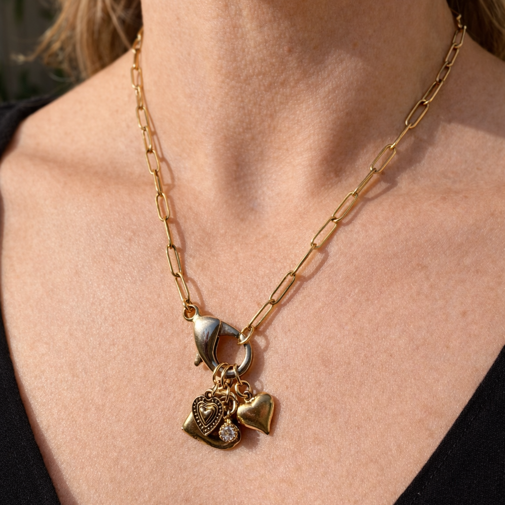 Gold necklace with heart-shaped pendants on a person wearing a black top.