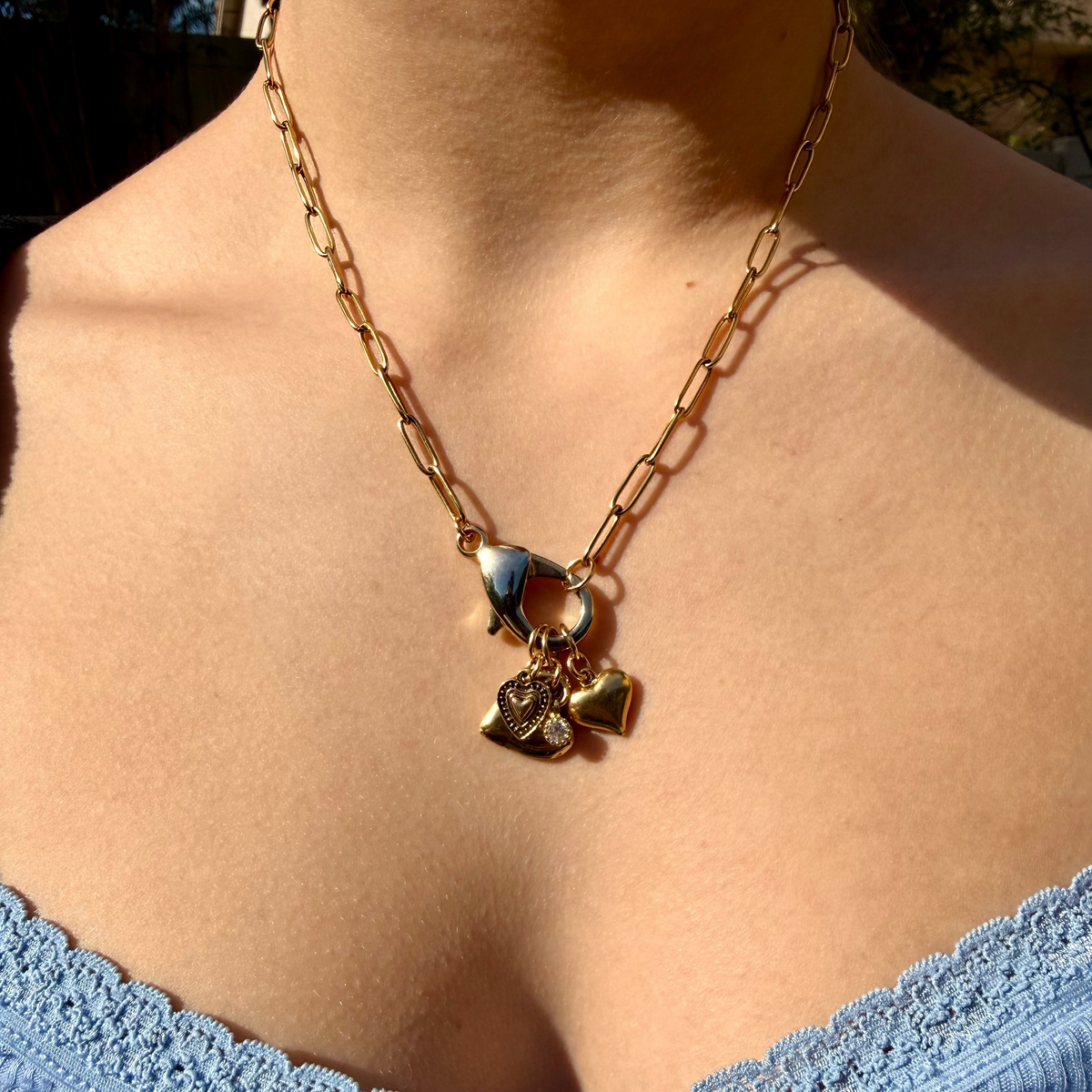 Necklace with heart-shaped pendant on a person wearing a blue top.