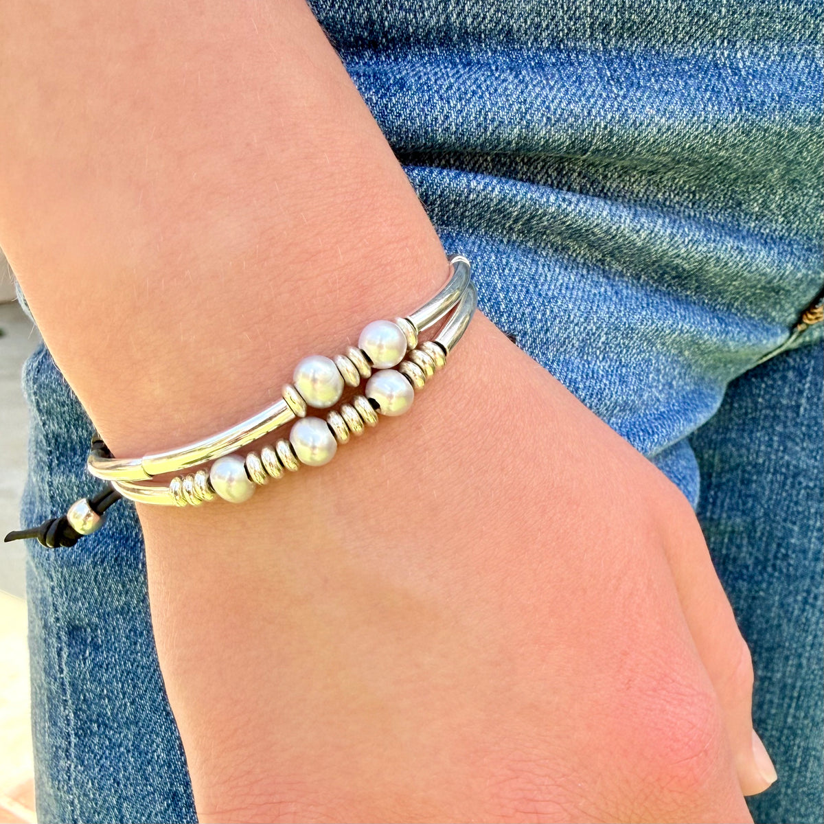 Silver beaded bracelet on a wrist with denim background