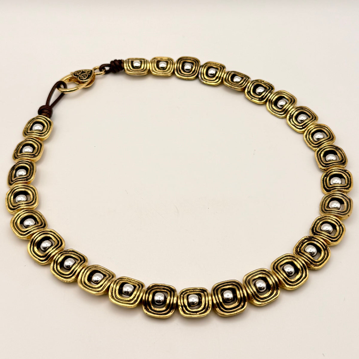 Gold necklace with circular beads on a beige background