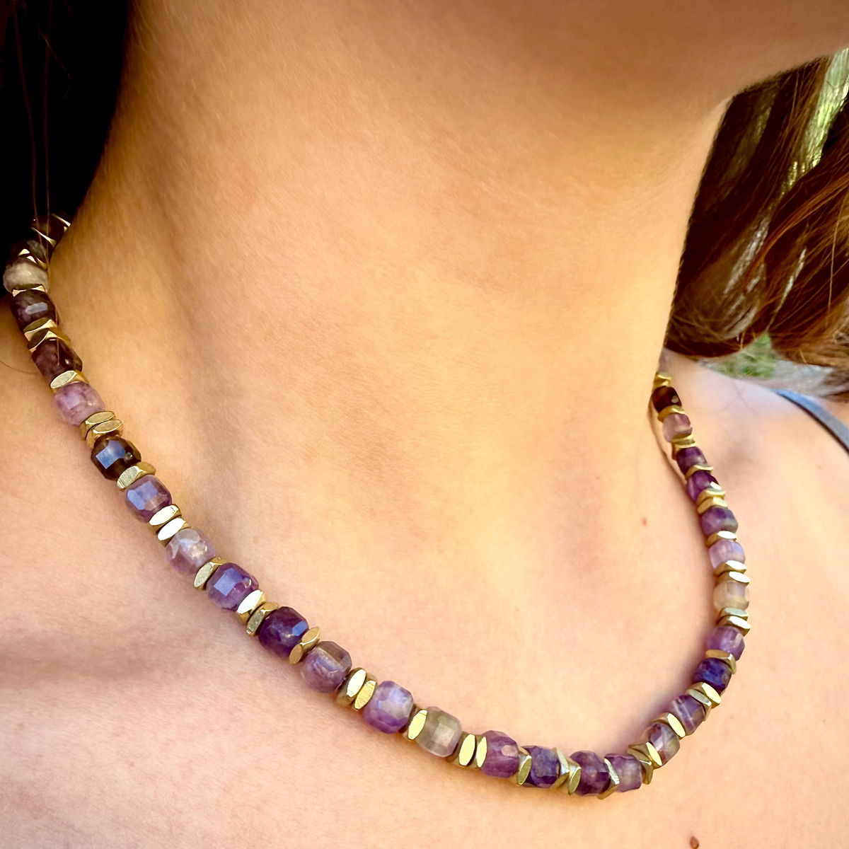 Necklace with purple and gold beads on a person's neck