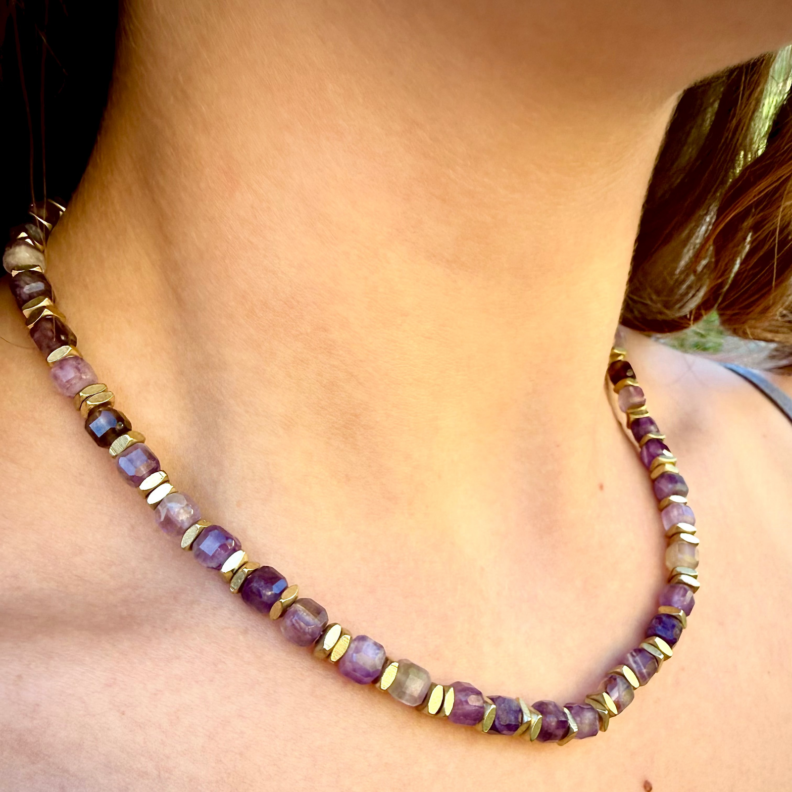 Necklace with purple and gold beads on a person's neck