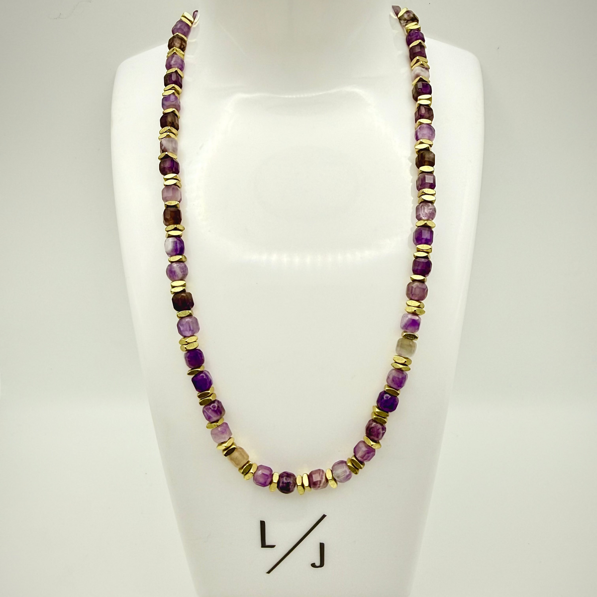 Necklace with purple and gold beads on a white mannequin bust with 'LJ' branding.