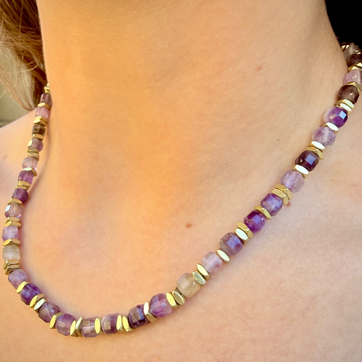 Necklace with purple and gold beads worn by a person
