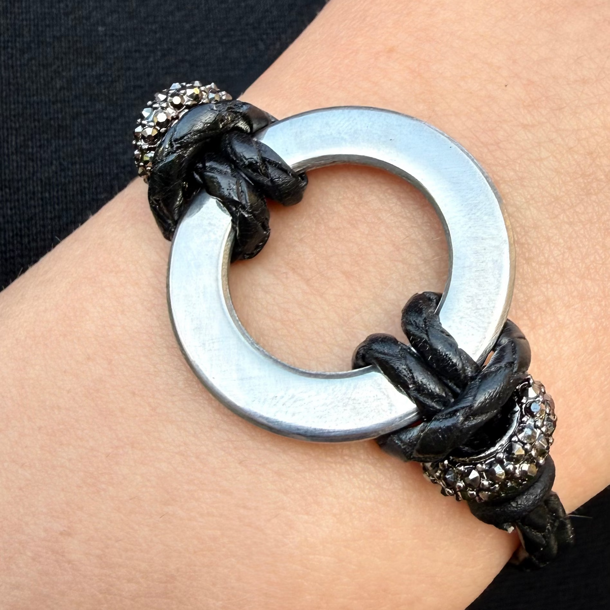 Women's double strand black leather bolo bracelet with a stainless steel infinity ring and pave rhinestone accent beads.