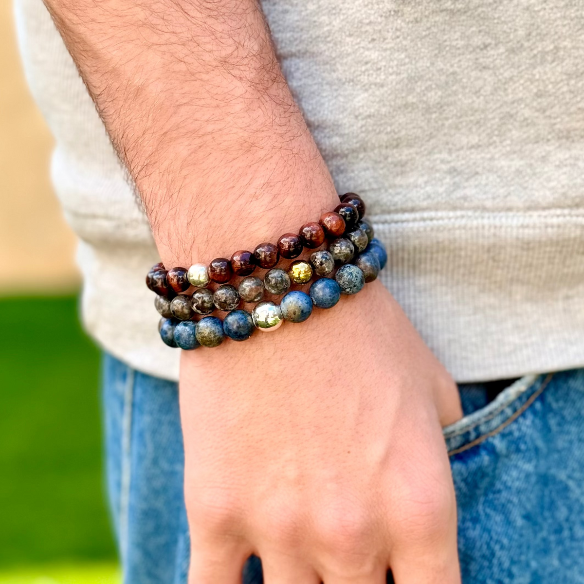 Person wearing a stack of beaded bracelets on a blurred natural background