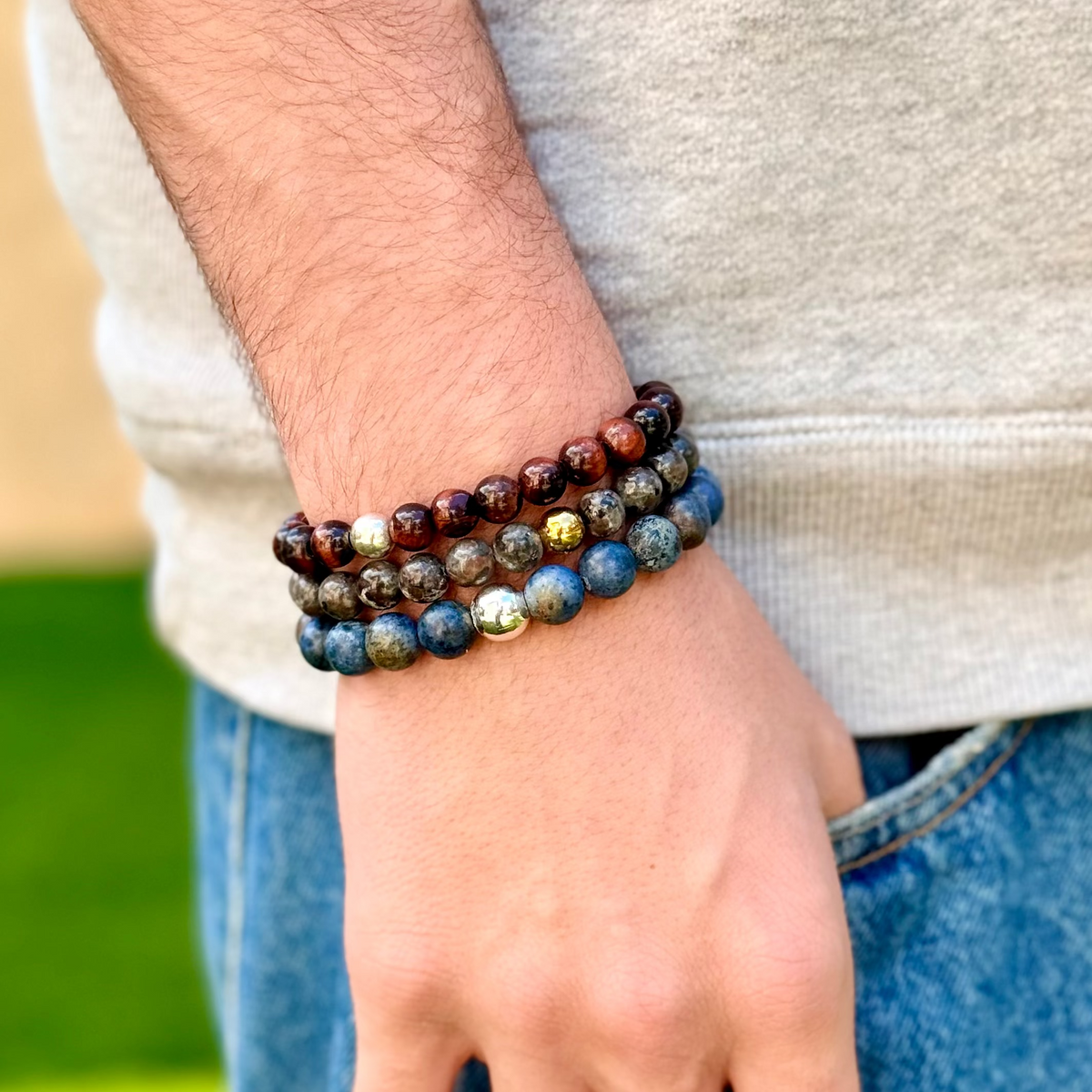 Person wearing a stack of beaded bracelets on a blurred natural background