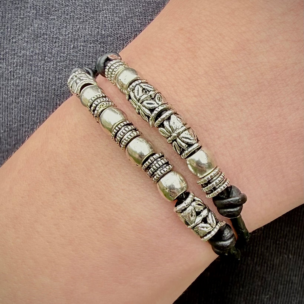 Silver beaded bracelet on a wrist with a gray background