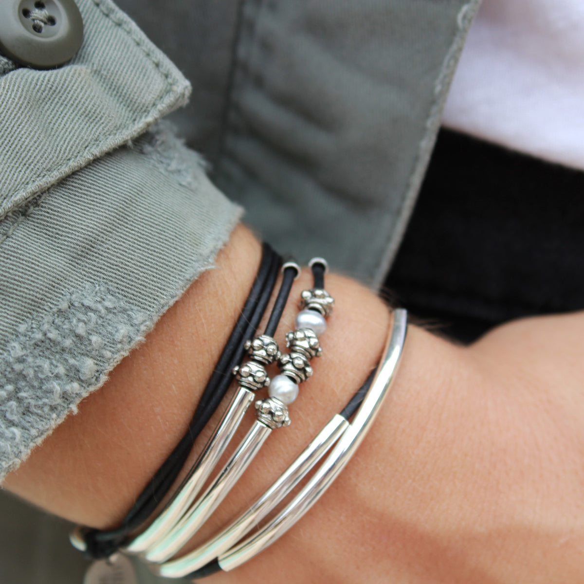 Close-up of a person's wrist wearing multiple bracelets with a blurred background