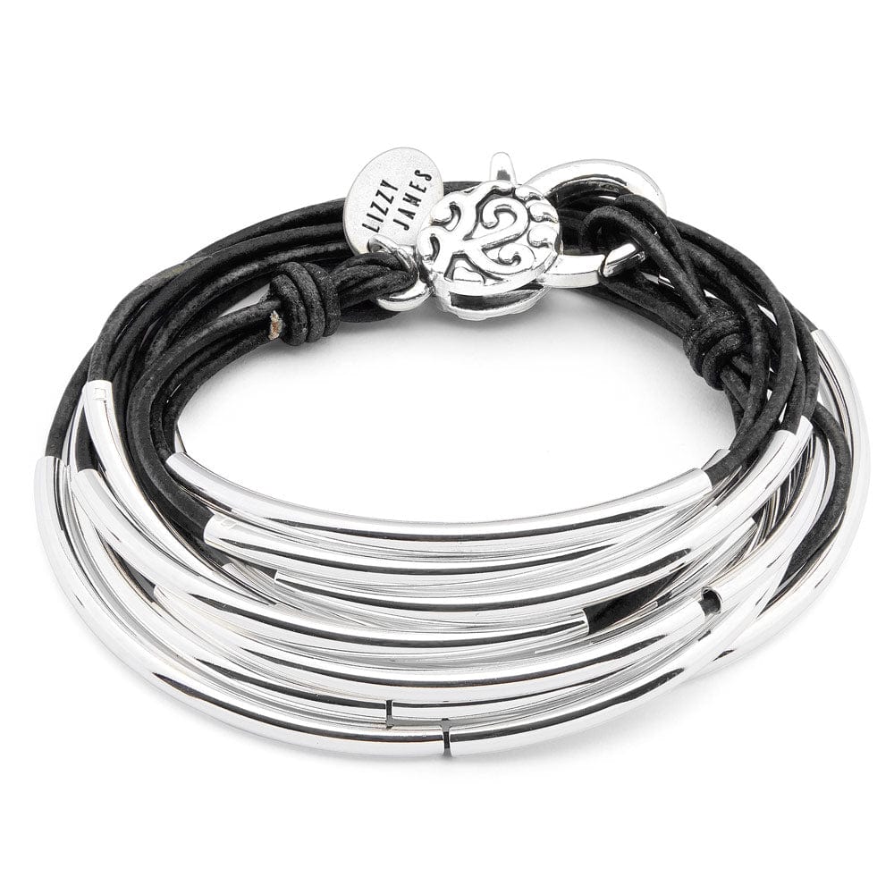 Close-up of a wrist wearing multiple silver bracelets with a blurred denim background.