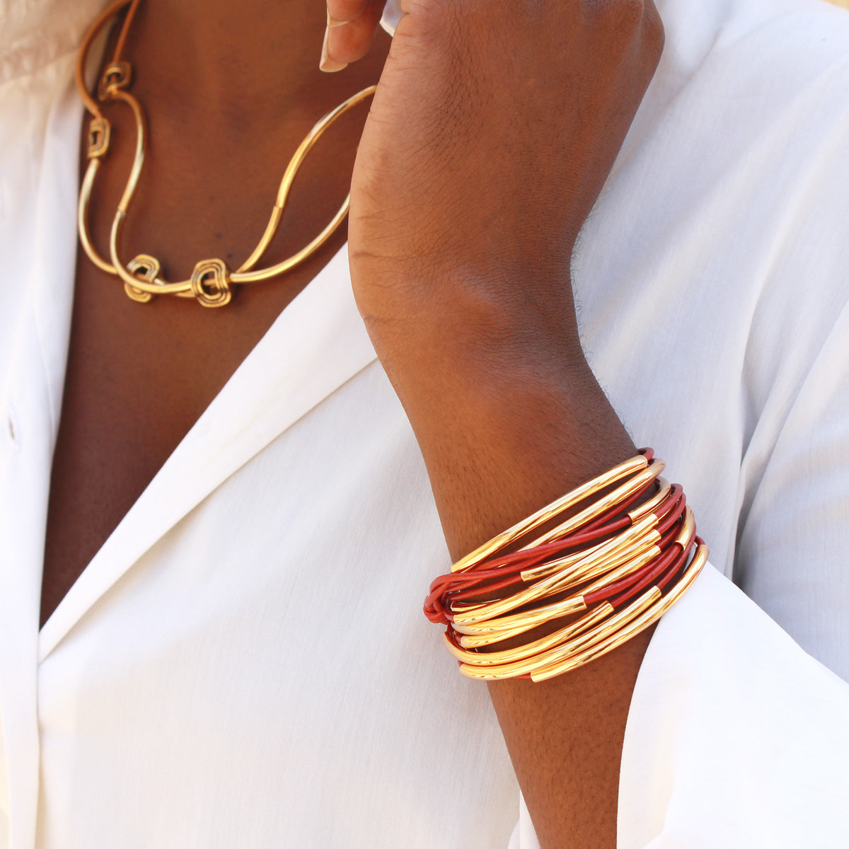 Close-up of a person wearing gold and red bracelets on a white background