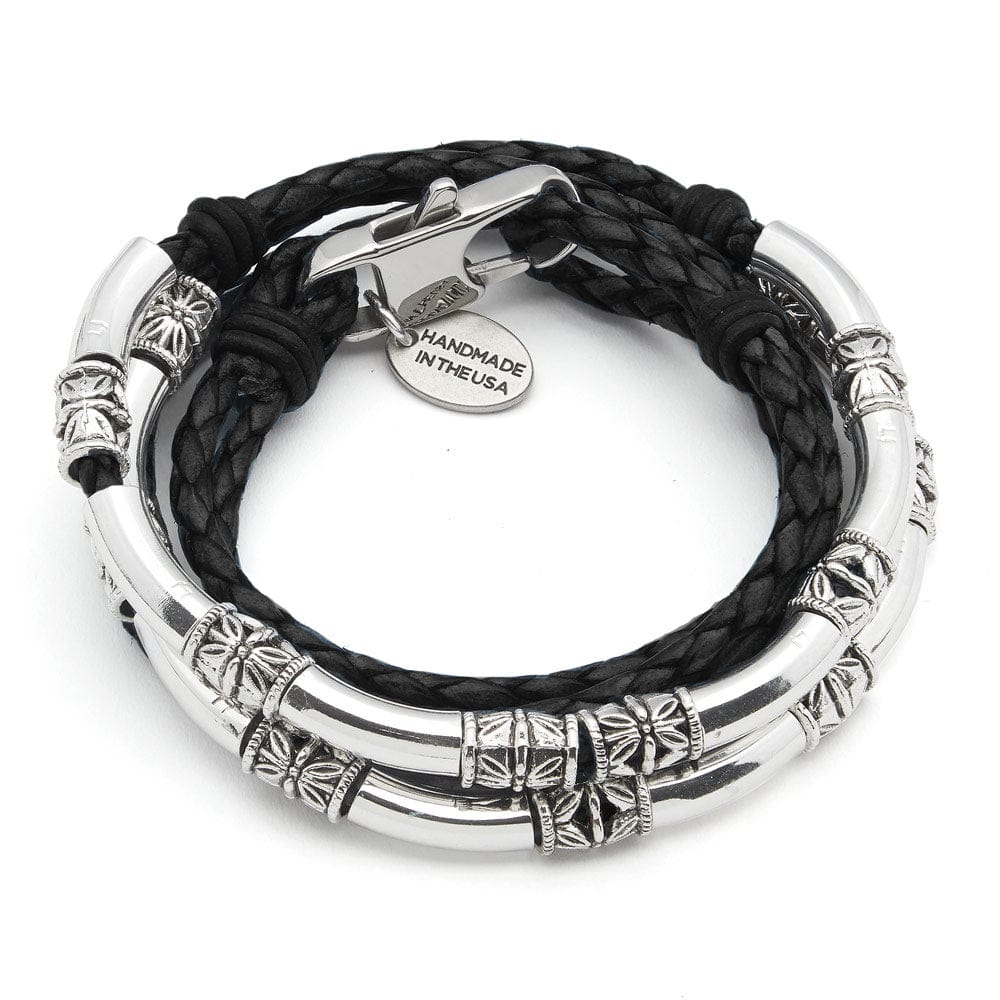 Close-up of a person wearing multiple silver bracelets on a black background