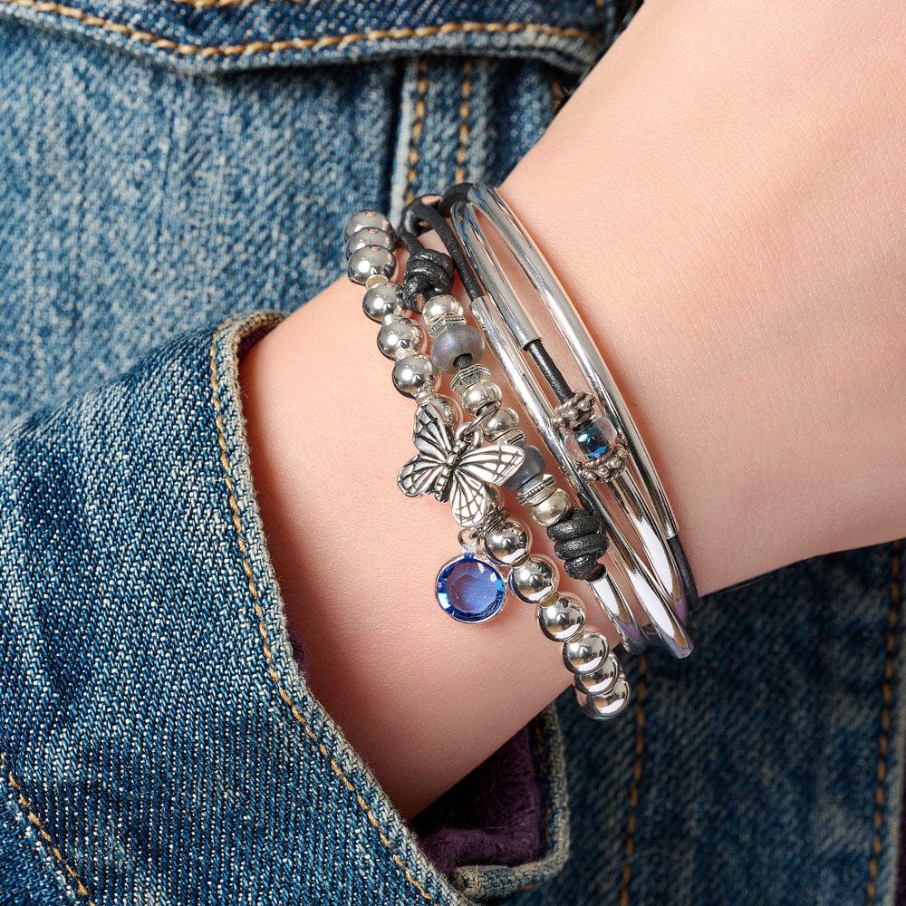 Mini Asha silver bracelet with butterfly charm next to Zenzi silver bead bracelet