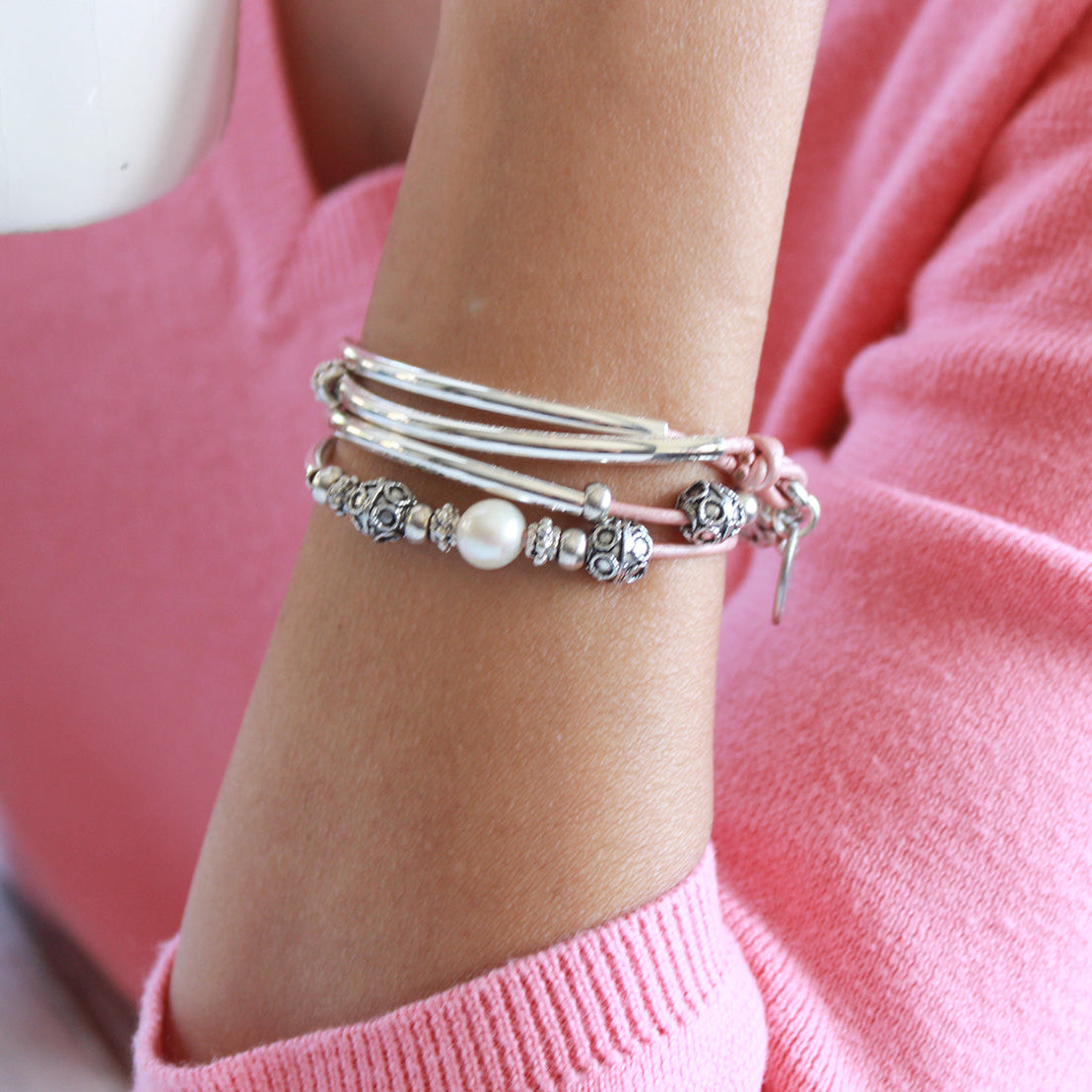 Leather wrap bracelet with pink leather, silver crescents and bead accessnts and a pearl focal.