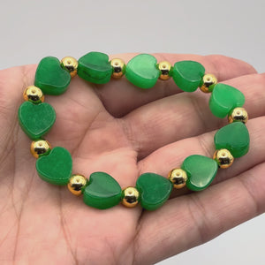 Close-up video of the Lila Emerald Jade Heart Bracelet with gold beads held in a hand. 