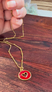 Dainty 18k gold-plated satellite chain necklace featuring a circular red enamel charm with a gold heart in the center.