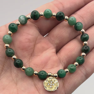 Video of Soleil Emerald Bracelet with Gold Starburst & Gemstone held in a hand showing the detail of the beads and charm.