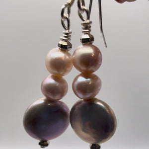 Video of hand holding pink and purple tone fresh water pearl earrings 