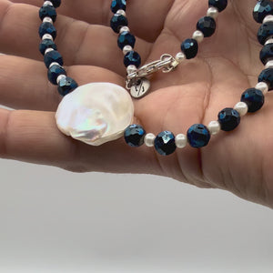 Video of hand holding a pearl neckalce with faceted blue iris druzy beads