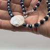 Video of hand holding a pearl neckalce with faceted blue iris druzy beads
