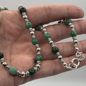 Vide of the Mira Emerald Gemstone necklace with silver accent beads held in a hand showing the detail.