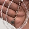 Close-up of a hand holding a clear crystal necklace held up close 