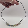 Video of a hand holding and showing the detail of a necklace with vintage silver tone beads and multi colored crystal dangles strung on black leather.